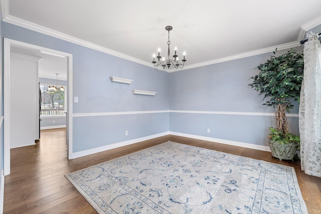 spare room with a chandelier, dark hardwood / wood-style flooring, and crown molding