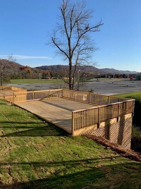 wooden terrace featuring a lawn and a mountain view