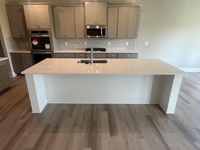 kitchen featuring decorative backsplash, sink, hardwood / wood-style floors, and appliances with stainless steel finishes