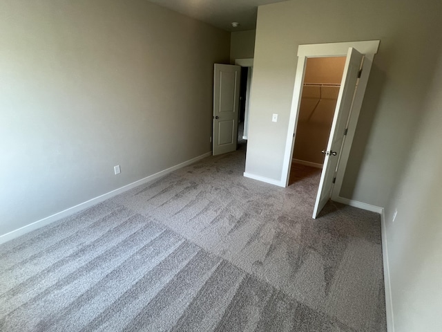 unfurnished bedroom featuring carpet, a walk in closet, and a closet