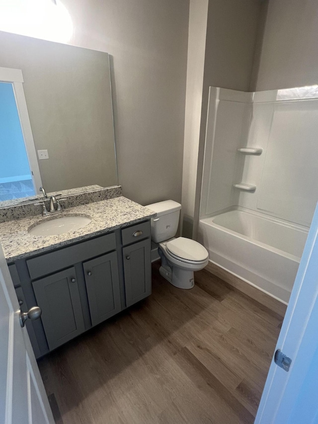 full bathroom featuring hardwood / wood-style flooring, vanity, toilet, and shower / tub combination