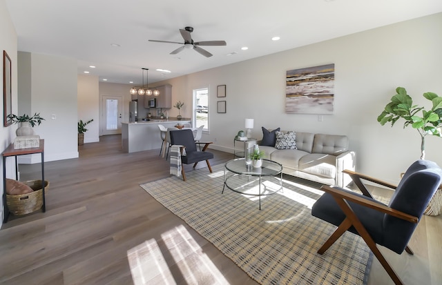 living room featuring wood-type flooring and ceiling fan with notable chandelier