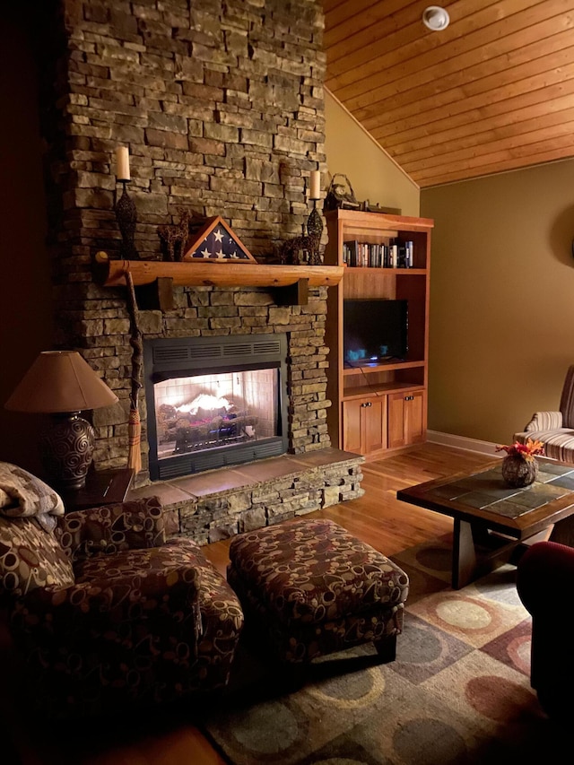 living room with lofted ceiling, a stone fireplace, wood-type flooring, and wooden ceiling