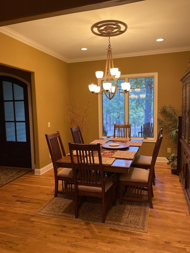 dining space with light hardwood / wood-style flooring, an inviting chandelier, and ornamental molding