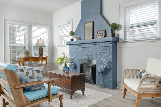 living area featuring a wood stove, light hardwood / wood-style flooring, and ornamental molding