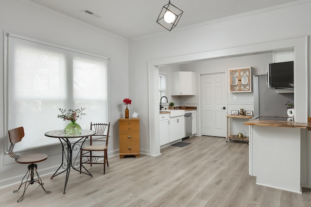 kitchen with wood counters, sink, ornamental molding, light hardwood / wood-style floors, and white cabinetry