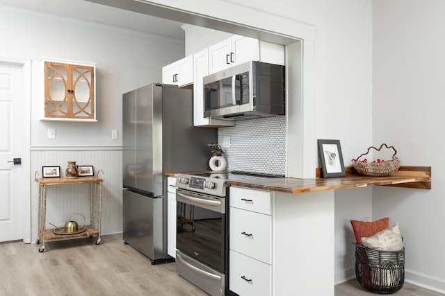 kitchen with wood counters, appliances with stainless steel finishes, light wood-type flooring, crown molding, and white cabinetry