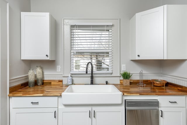 kitchen featuring white cabinets, butcher block countertops, stainless steel dishwasher, and sink