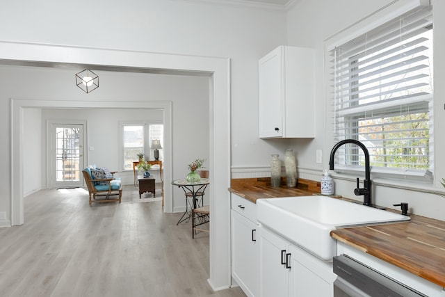 kitchen with ornamental molding, dishwashing machine, sink, white cabinets, and light hardwood / wood-style floors