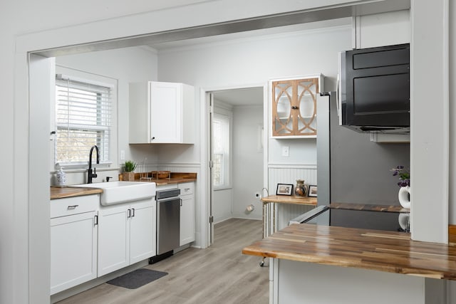 kitchen with light wood-type flooring, white cabinetry, butcher block counters, and sink