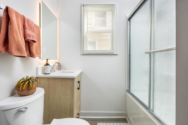 full bathroom with hardwood / wood-style flooring, combined bath / shower with glass door, toilet, and vanity