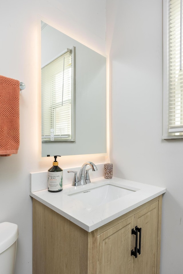 bathroom with vanity, a healthy amount of sunlight, and toilet