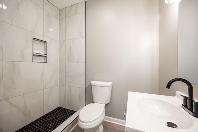 bathroom with tiled shower, vanity, toilet, and hardwood / wood-style floors