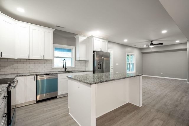 kitchen with sink, a kitchen island, white cabinets, and appliances with stainless steel finishes