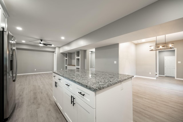 kitchen featuring stainless steel refrigerator with ice dispenser, decorative light fixtures, light stone counters, and white cabinets