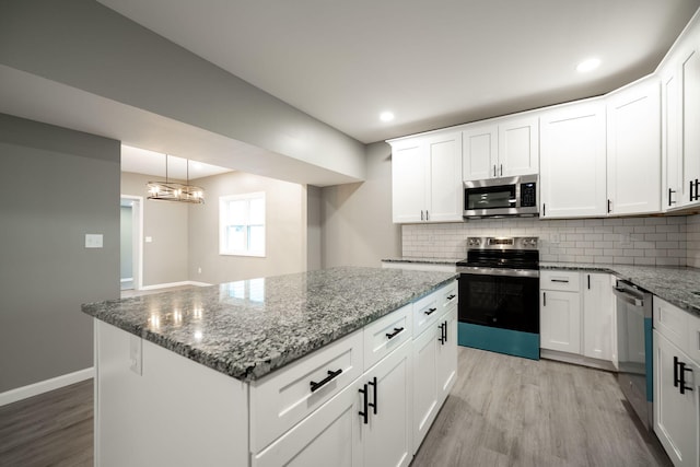 kitchen featuring pendant lighting, stainless steel appliances, backsplash, and white cabinets