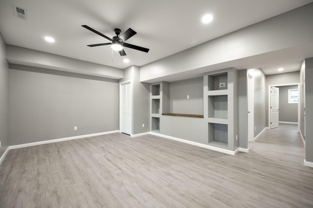 unfurnished living room featuring built in shelves, light hardwood / wood-style flooring, and ceiling fan