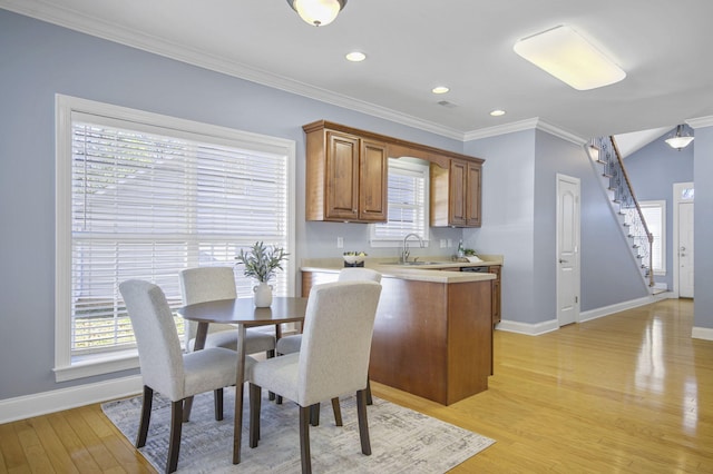 dining area with sink, light wood-type flooring, and crown molding