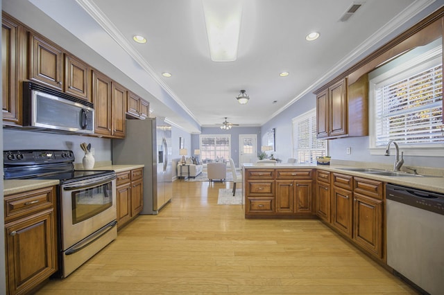 kitchen with appliances with stainless steel finishes, light wood-type flooring, ceiling fan, and sink