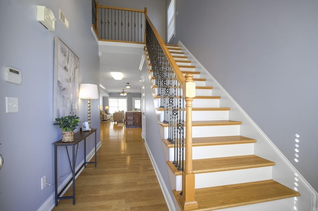 stairway featuring ceiling fan, wood-type flooring, and a towering ceiling