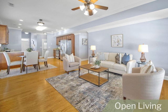 living room with ceiling fan, light wood-type flooring, and ornamental molding