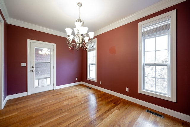 unfurnished dining area with ornamental molding, light wood-type flooring, plenty of natural light, and a notable chandelier