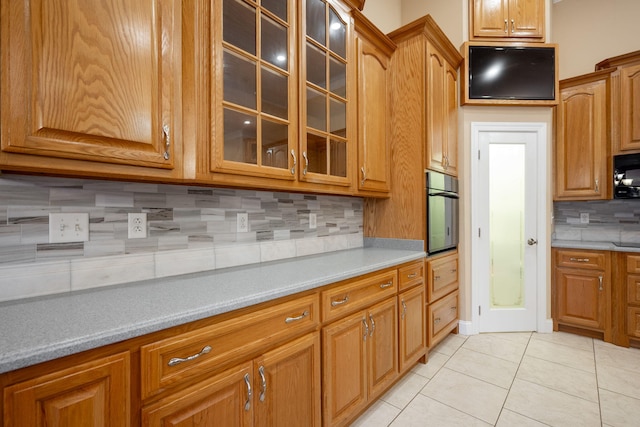 kitchen featuring backsplash, stainless steel oven, and light tile patterned floors