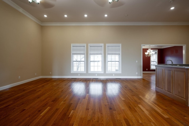 unfurnished living room featuring hardwood / wood-style flooring, ceiling fan with notable chandelier, and crown molding