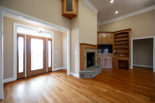 entryway featuring a fireplace, an inviting chandelier, light hardwood / wood-style flooring, and crown molding