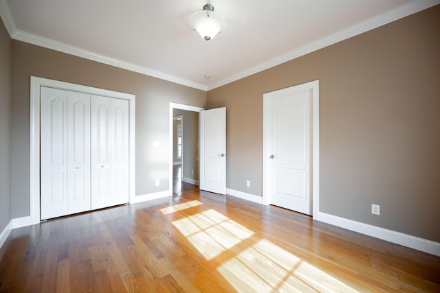 unfurnished bedroom with wood-type flooring, crown molding, and a closet