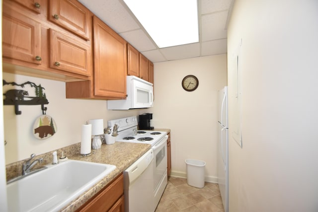 kitchen with a drop ceiling, white appliances, and sink