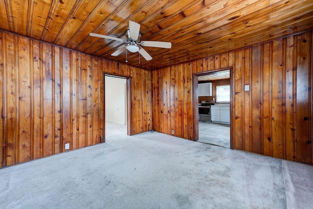 empty room with ceiling fan, light colored carpet, wood ceiling, and wooden walls