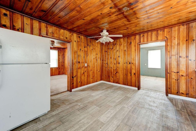 unfurnished dining area with wood walls, ceiling fan, light hardwood / wood-style floors, and wooden ceiling