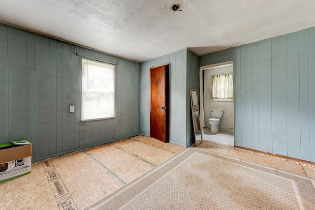 bedroom featuring connected bathroom and wood walls