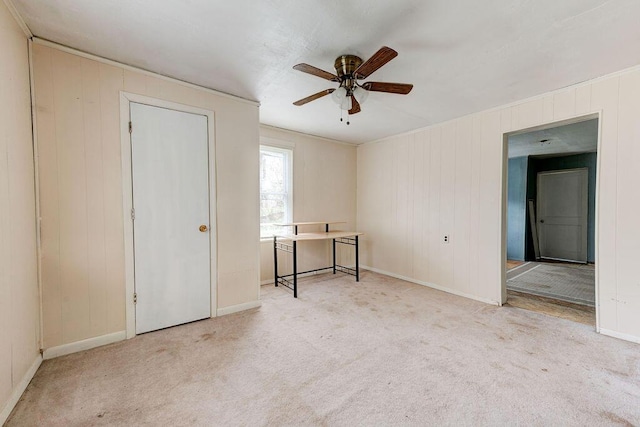 carpeted spare room featuring ceiling fan and wood walls