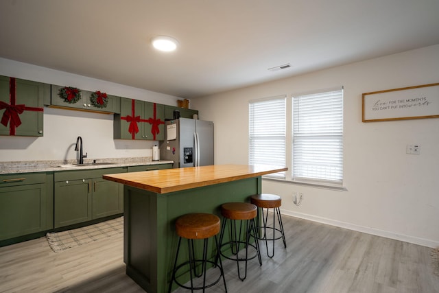 kitchen featuring wooden counters, stainless steel fridge, sink, light hardwood / wood-style floors, and a kitchen island