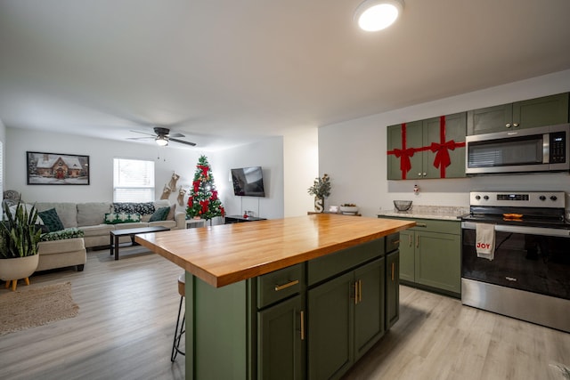 kitchen with green cabinets, wooden counters, stainless steel appliances, and light hardwood / wood-style floors