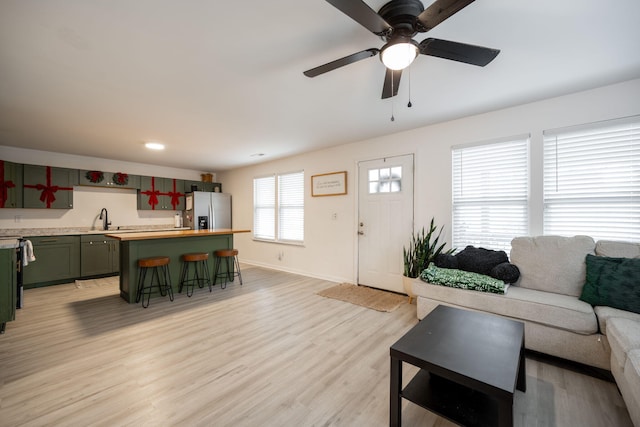 living room featuring ceiling fan, sink, and light hardwood / wood-style flooring