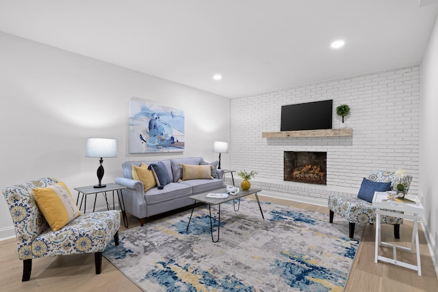 living room with brick wall, baseboards, recessed lighting, a fireplace, and wood finished floors