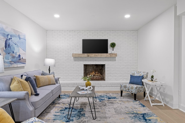 living area featuring recessed lighting, a brick fireplace, baseboards, and wood finished floors