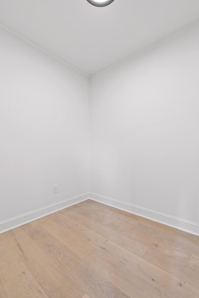 spare room featuring baseboards and light wood finished floors