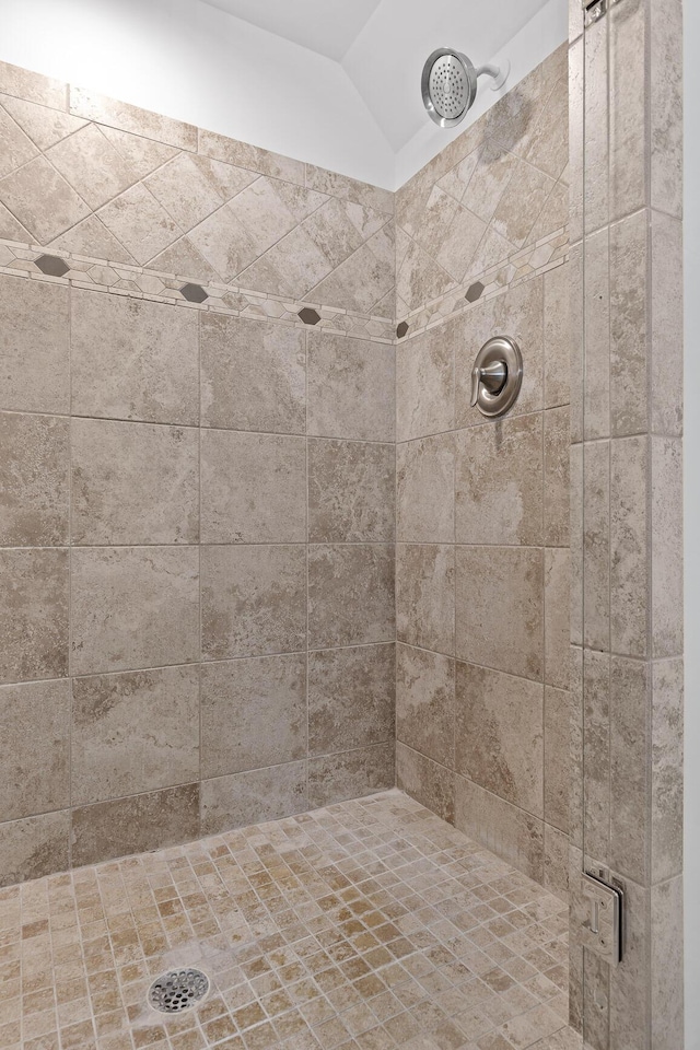 bathroom with tiled shower and vaulted ceiling