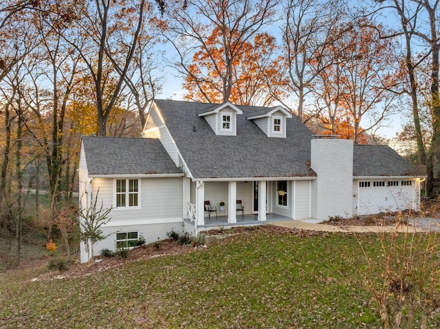 view of front of property with an attached garage, a front lawn, and roof with shingles