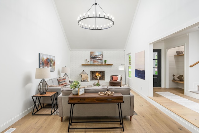 living room with stairway, light wood finished floors, a fireplace, crown molding, and a chandelier