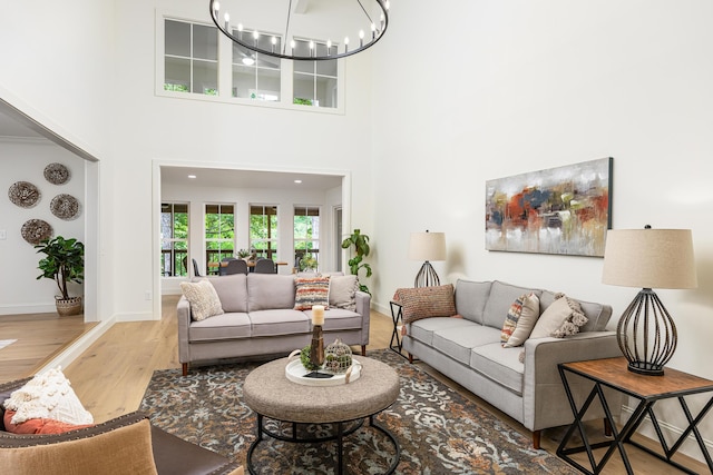 living room featuring baseboards, a high ceiling, an inviting chandelier, and wood finished floors