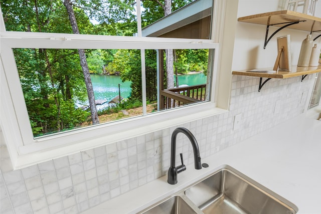 details with open shelves, a water view, tasteful backsplash, and light countertops