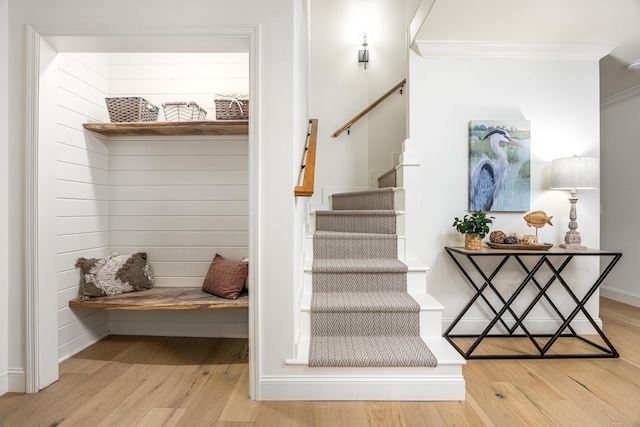 stairs with baseboards, wood finished floors, and ornamental molding