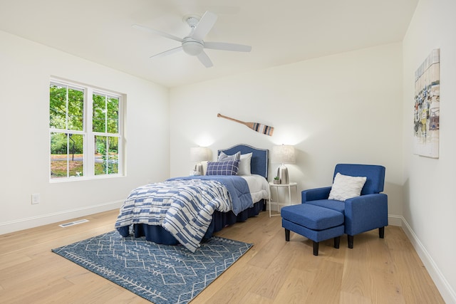 bedroom with ceiling fan, wood finished floors, visible vents, and baseboards