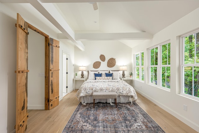 bedroom with lofted ceiling with beams, baseboards, and light wood finished floors