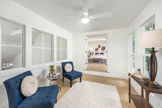 living area featuring light wood-type flooring, baseboards, and a ceiling fan